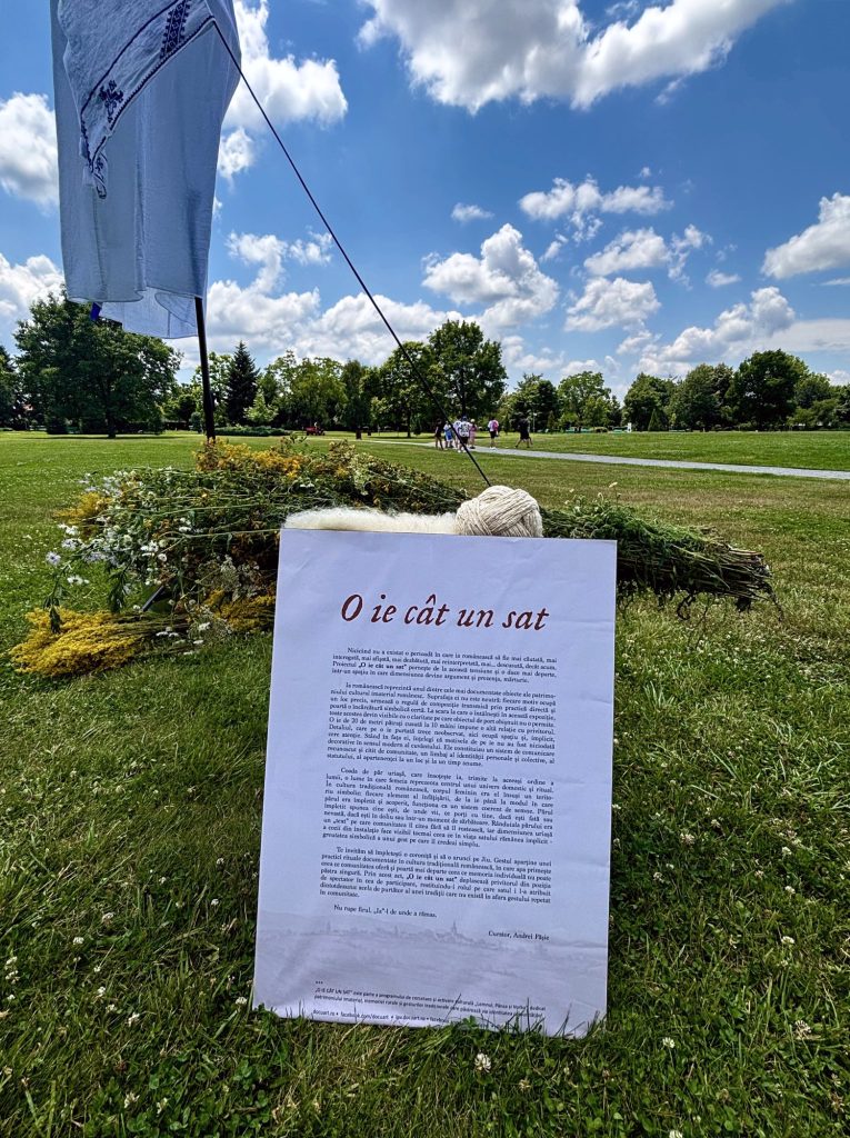 Wall text for O ie cât un sat on the grass beside a wreath of plants