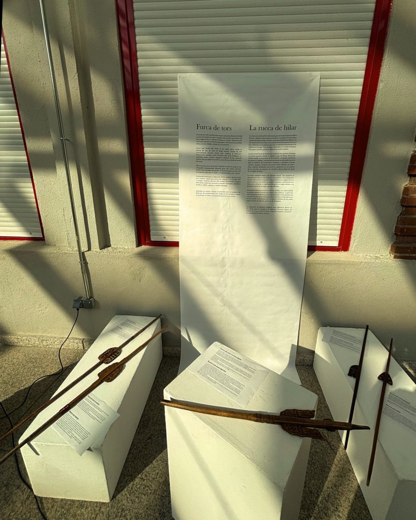 Spinning distaffs on white plinths with wall texts