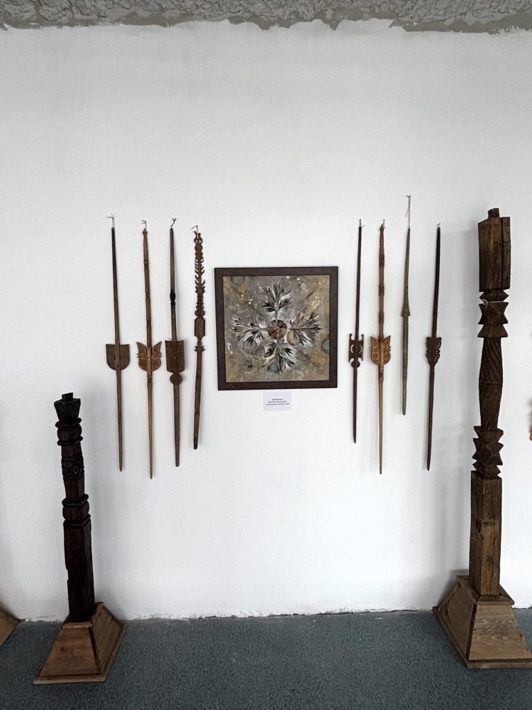 Wooden pillars and distaffs around the painting Axis Mundi