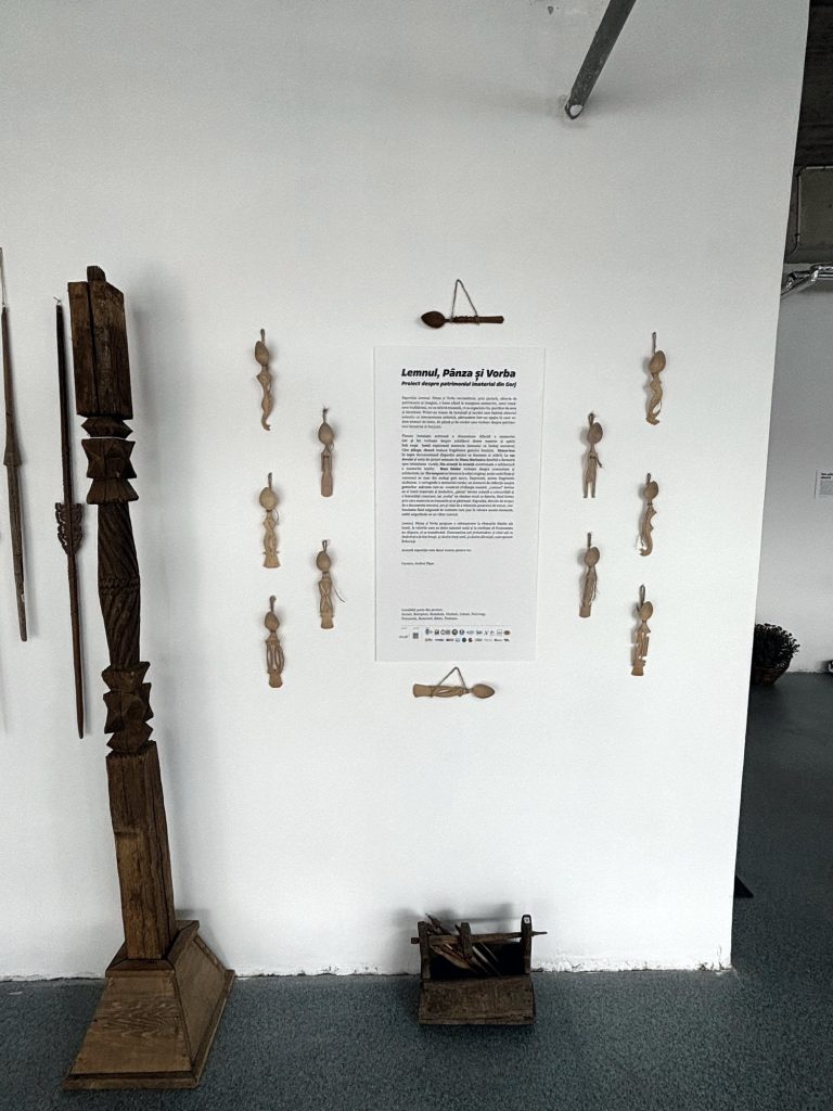 Carved pillar and wooden spoons with the wall text of Sub coaja lumii