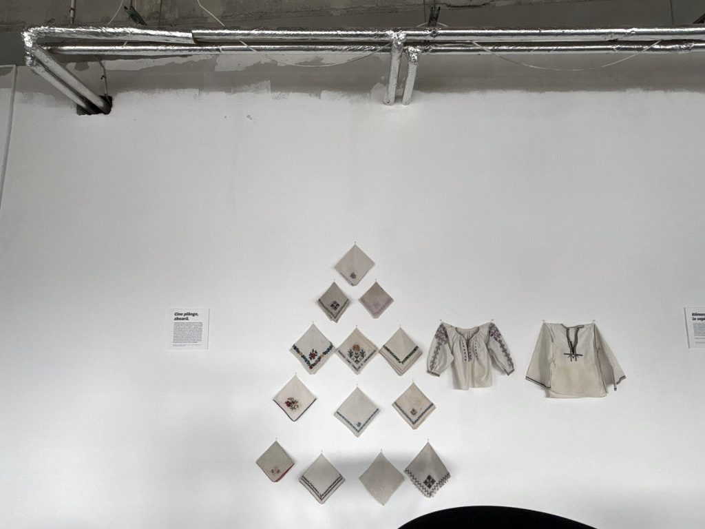 Traditional handkerchiefs arranged in a diamond next to two blouses in Cine plânge, zboară